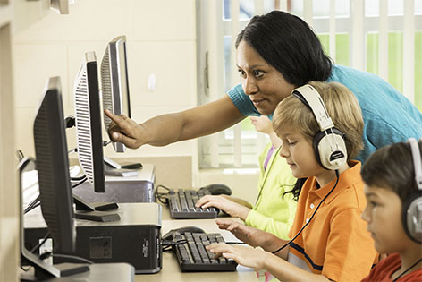 teacher helping students with headsets